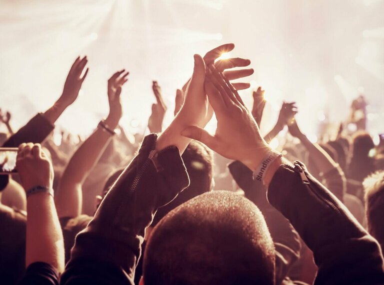 eine Menschenmenge, die die Hände in die Luft streckt und applaudiert